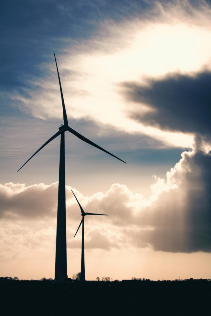 Aerogenerador contra un cielo con nubes y rayos de sol.